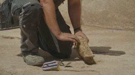 Jan Heiler examines an archaeological find at the dig site in Mosul, Iraq. (Windfall Films/Ali Hilal Ali Hussain)