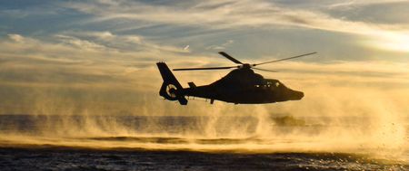 A Customs surveillance helicopter flies over the sea at sunset. (Agencia Tributaria)