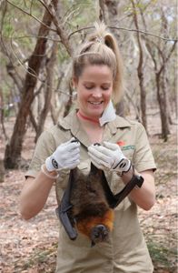 Sarah Curran holding a bat upside down in the forest. (Big Wave Productions)