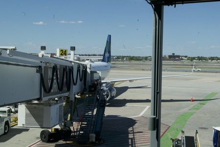 A boarding ramp is sitting attached to an airplane that is parked on the JFK International Airport tarmac.(National Geographic)