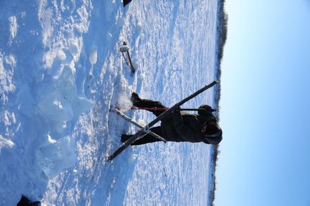 Avery Hoffman picks a hole in the ice to set their fish nets. (BBC Studios Reality Productions, LLC/Isaiah Branch - Boyle)