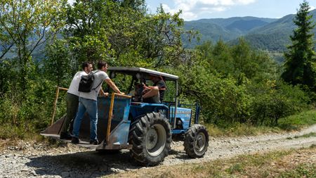 Justin Theroux and Antoni Porowski ride on the back of Eugenio Franchi's tractor. (National Geographic/Rebecca Eishow)