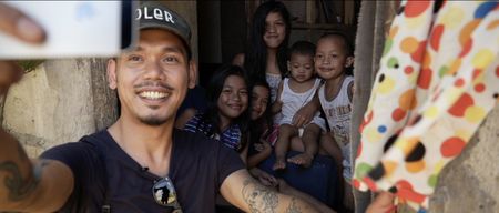 Manila, Philippines - Photographer Carlo Gabuco takes a selfie with a group of children. (Genius Loki Film and Violet Films/Alexander A. Mora)