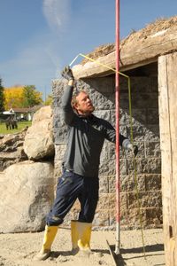 Ben Reinhold uses a tape measure to measure the length between the ground and the roof of the farm's sheep hut. (National Geographic)