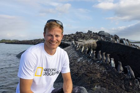 Bertie Gregory against a backdrop of Galapagos penguins and Galapagos Marine iguanas.(credit: National Geographic/Javier Mahauad)