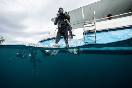 Cinematographer Rory McGuinness enters the water in preparation to film the Coconut octopus (Amphioctopus marginatus) in Lembeh Strait. (National Geographic for Disney/Craig Parry)