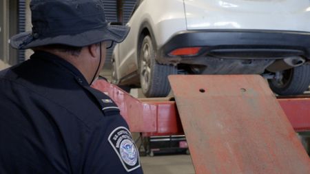 CBP Officer Torres raises a passenger's vehicle on a lift to better inspect the underside for hidden contraband in Calexico,  Calif. (National Geographic)