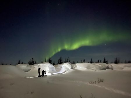 Director of photography Simon Niblett films the aurora borealis from behind a snow bank.   (National Geographic for Disney/Duncan Chard)