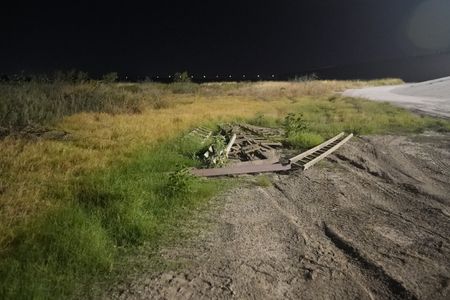 Broken wood ladders lie on the ground near the border wall in the Rio Grande Valley, Texas. (National Geographic)