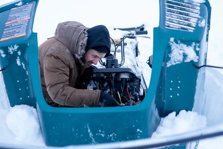 Johnny Rolfe fixes the carburetor on his snowmobile, and dethaws the frozen lines after it broke down in the wilderness. (BBC Studios Reality Productions/Tyler Colgan)