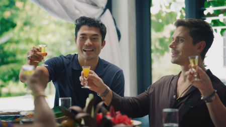 Henry Golding and Antoni Porowski cheers Tuak at the family meal. (National Geographic)