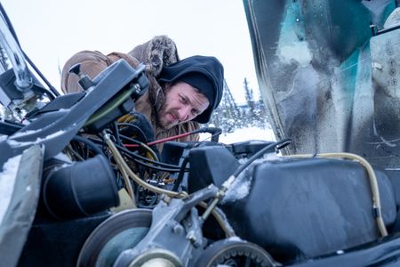 Johnny Rolfe fixes his snowmobile after it breaks down in the deep snow. (BBC Studios Reality Productions/Tyler Colgan)