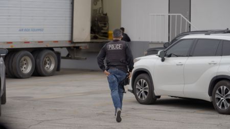 An HSI agent wearing a bulletproof vest runs to make an arrest during an operation in San Diego, Calif. (National Geographic)