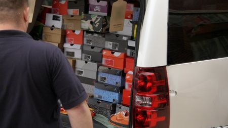 HSI Agent Jonathan looks inside the trunk of a suspect's vehicle and finds multiple boxes of suspected counterfeit shoes in Kansas City, Mo. (National Geographic)