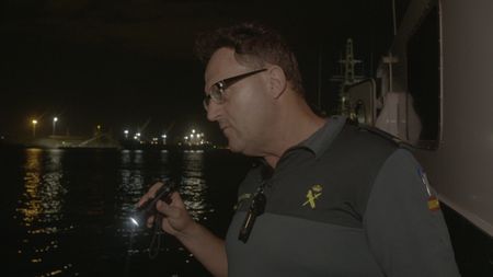 A guard inspects a vessel with a flashlight in AlmerÌa, Spain.  (National Geographic)