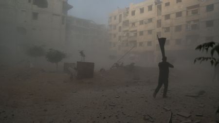 Al Ghouta, Syria - Dust and debris fill the air during an attack outside the entrance to the hospital. (National Geographic)