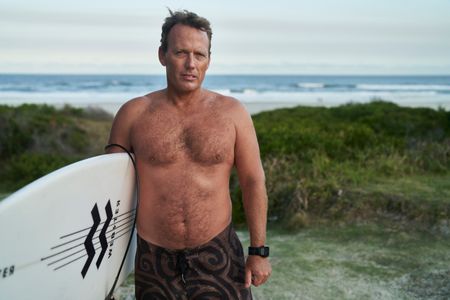 Lee Jonsson with his surfboard at Shelly Beach. (National Geographic/Justine Kerrigan)