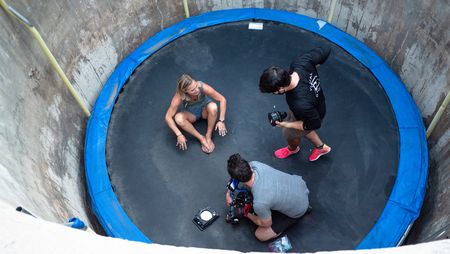 Angel Collinson sits on the trampoline as cinematographer Nick Kraus and assistant cameraperson Galen Murray change a lens.   (National Geographic/Elena Gaby)