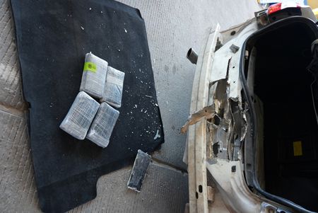 Multiple packages of suspected narcotics were placed on the ground after they were discovered smuggled in the rear bumper of a suspect's vehicle in El Paso, Texas. (National Geographic)