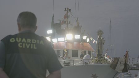 A guard watches from the bridge of a patrol boat the Procession of the Virgin of the Sailors in Barbate, C·diz, Spain.  (National Geographic)