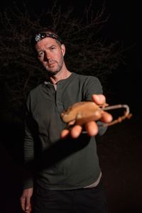 Giles Clark holds a pangolin radio telemetry tag. (National Geographic/Mark Challender)