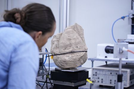 Katharina Schmidt examines the recently unearthed stone head at the SESAME laboratory. (Windfall Films/Alex Collinge)