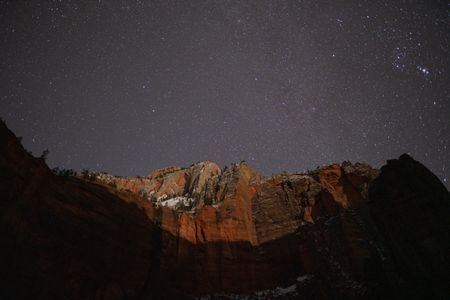 Under the canopy of a night sky, moonlight illuminates the red sandstone cliffs of Zion National Park.  (National Geographic/Jeff Reed)