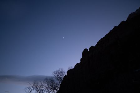 A sliver of moon hangs in a dusky purple sky in Zion.  (National Geographic/Jeff Reed)