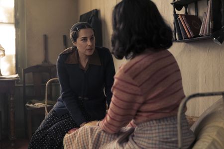 A SMALL LIGHT - Edith Frank, played by Amira Casar, speaks with Miep, played by Bel Powley, in the annex in A SMALL LIGHT. (Credit: National Geographic for Disney/Dusan Martincek)