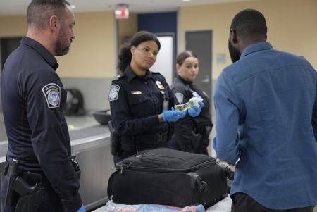 CBP Officer Laska is looking on as CBP Officers Evans and Mccants question a passenger while going through their belongings in Atlanta, Ga. (National Geographic)