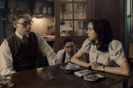 A SMALL LIGHT - Jan, played by Joe Cole, Kuno, played by Preston Nyman, and Miep, played by Bel Powley, gather money to try to help the Franks as seen in A SMALL LIGHT. (Credit: National Geographic for Disney/Dusan Martincek)