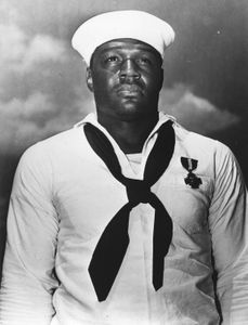 Doris Miller is seen in close-up portrait. "Erased: WW2's Heroes of Color" tells the stories of three Black heroes who miraculously survived the attack on Pearl Harbor. Miller served as mess attendant on the USS West Virginia, where he pursued boxing as a sport. He defied racial stereotypes when he shot down enemy planes during the attack. (National Archives and Records Administration)